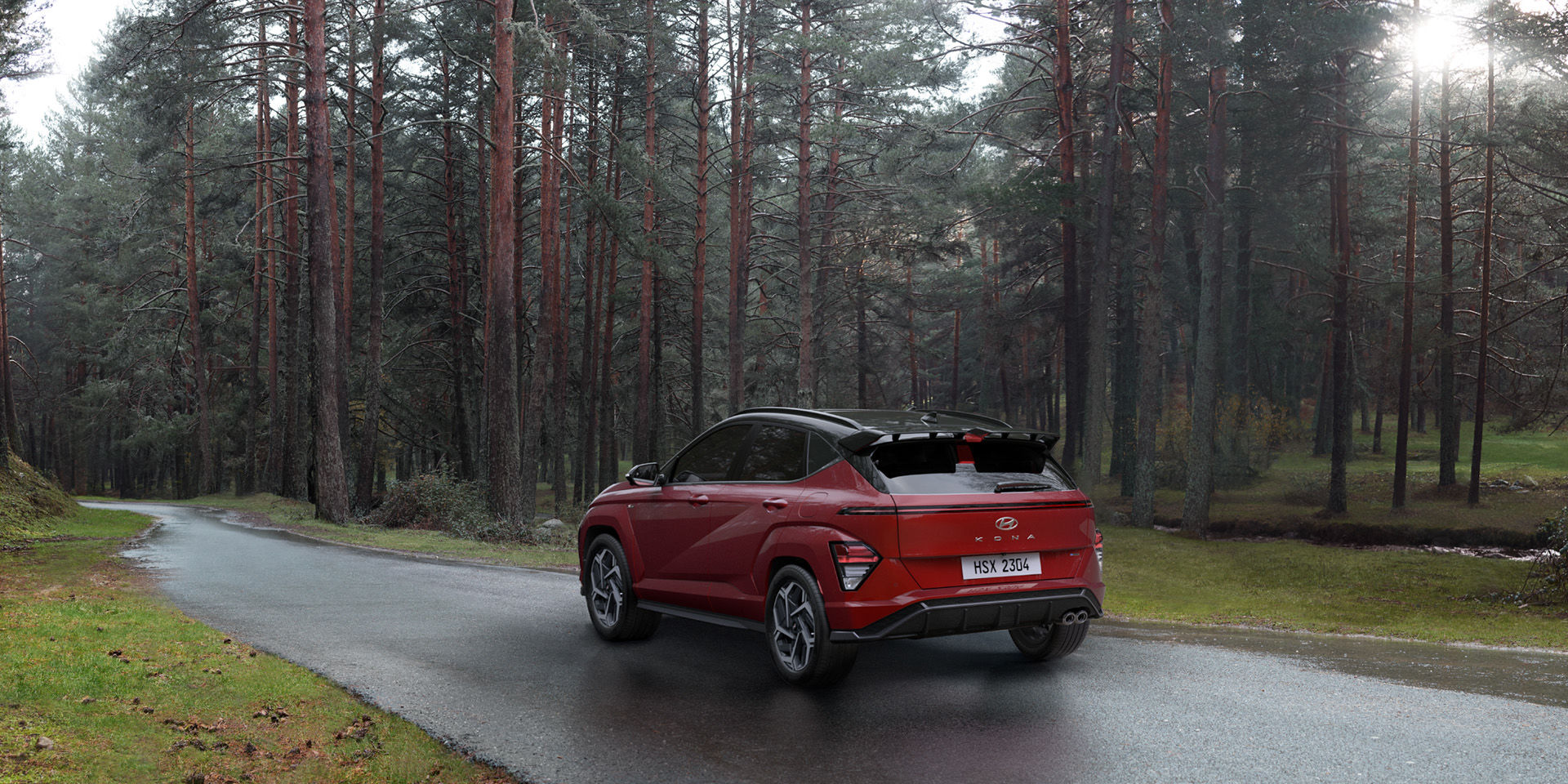 The back of a red The all-new KONA driving on a road in the forest