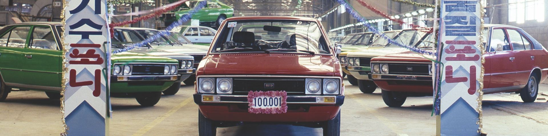 The original red PONY facing forward with a number plate "100.001" written on the front. The PONY is surrounded by other PONYs in different colors on both sides.